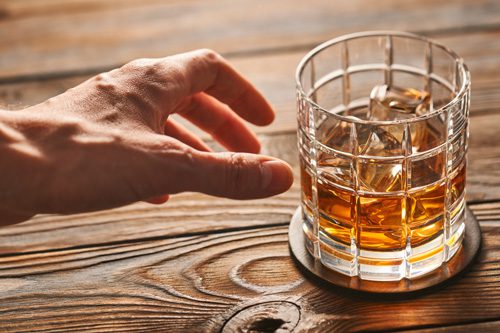 7 Reasons Relapse Happens - hand reaching for a drink