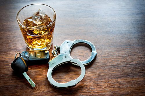 glass of liquor next to car keys and handcuffs - dui