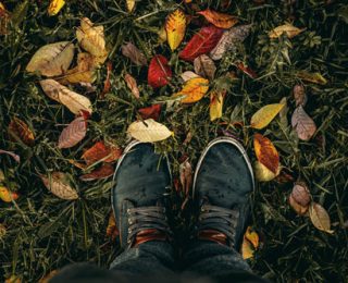 Guide to Celebrating Your First Sober Thanksgiving, man's feet standing on grass with fall colored leaves - thanksgiving