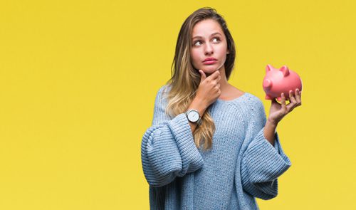 pretty young woman holding pink piggy bank on bright yellow background - paying