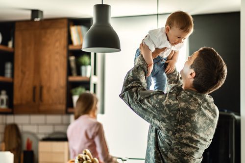 military man holding son in kitchen at home - veterans and substance use disorder