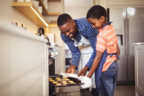 handsome Black dad baking cookies with his young son - hobbies