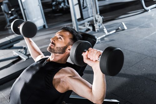 man in his early thirties lifting free weights at a gym or home gym - getting fit