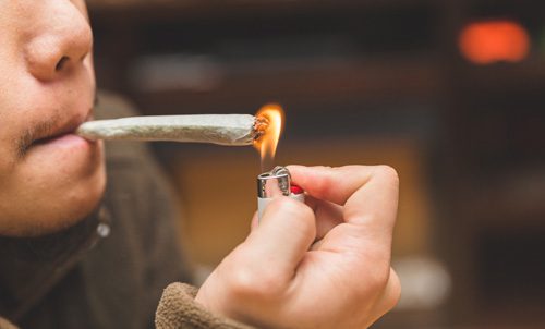 cropped shot of someone lighting a marijuana joint