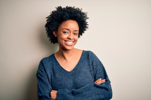 beautiful Black woman smiling at camera with her arms crossed - persistence