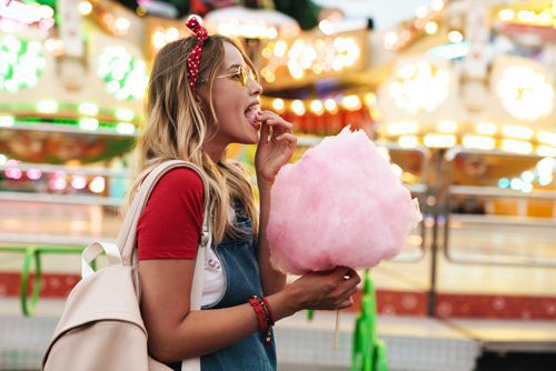 beautiful young woman at a fair eating cotton candy - sugar and recovery